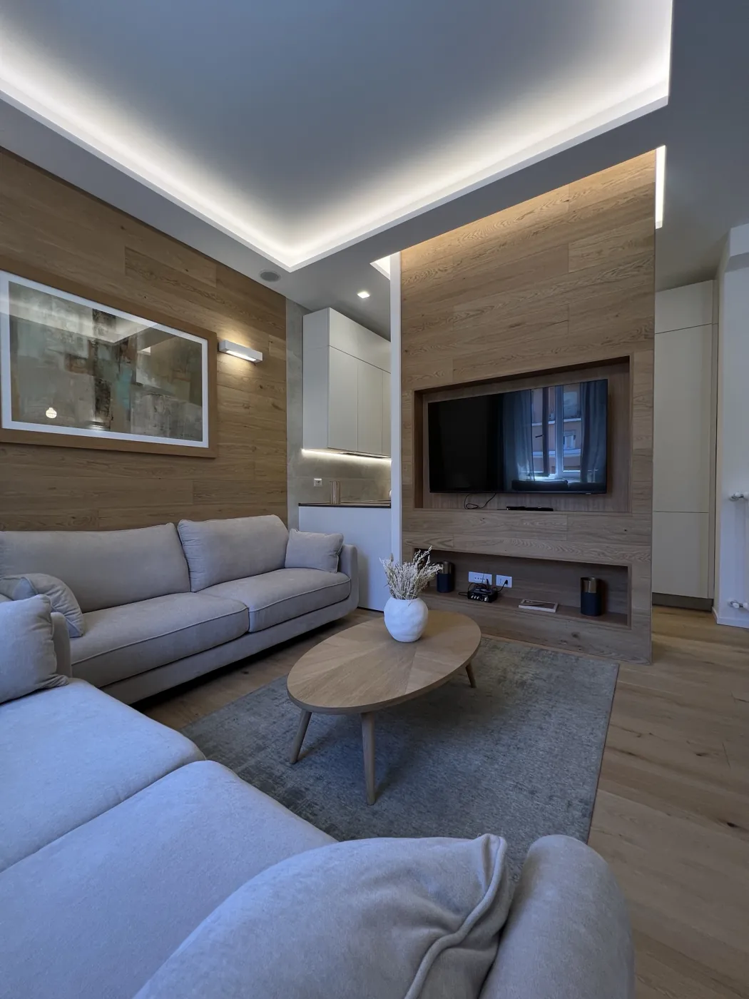 Soggiorno con boiserie in rovere, parete TV integrata e controsoffitto luminoso, Roma Corso Francia