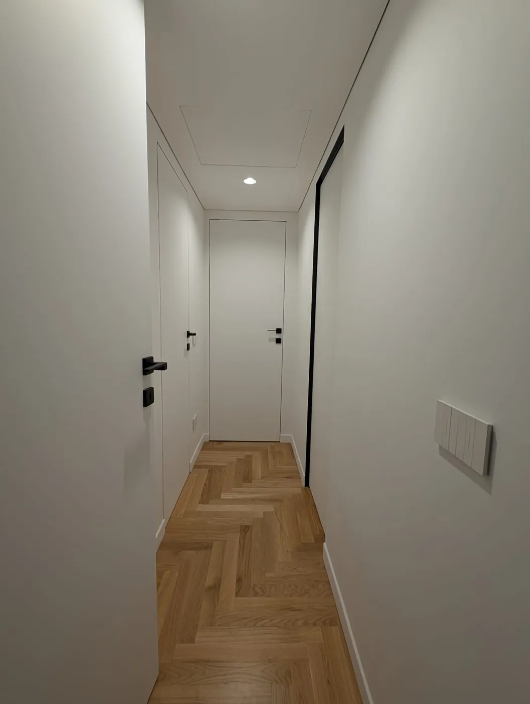 Disimpegno con porte filo muro, maniglie nere e parquet a spina di pesce, Roma Via Cassia