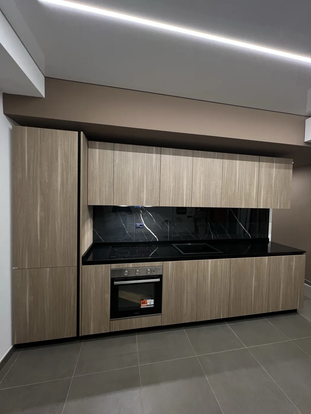 Cucina lineare in legno con top e alzatina effetto marmo nero e taglio di luce LED, Roma Porta Pia